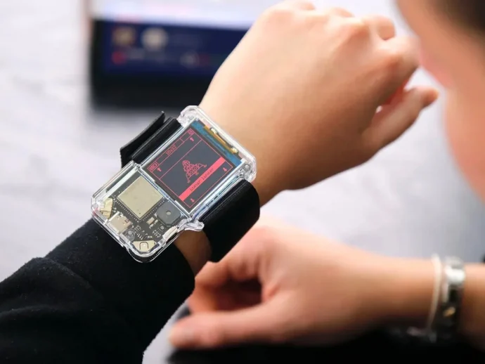Transparent smartwatch on the wrist showcasing exposed internal circuitry during a demonstration.