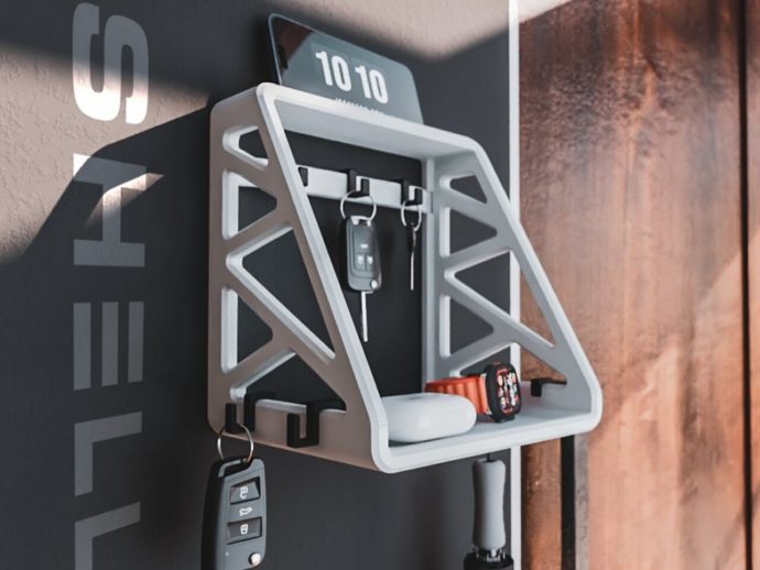 White geometric wall-mounted key shelf holding car keys and other keys on a dark wall
