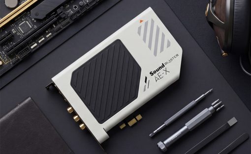 Sound Blaster AE-X external sound card on a dark desk with precision tools and headphones nearby.