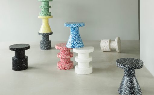 Colorful speckled terrazzo stools arranged in a gallery, stacked and standing, in black, white, red, blue, yellow, green tones