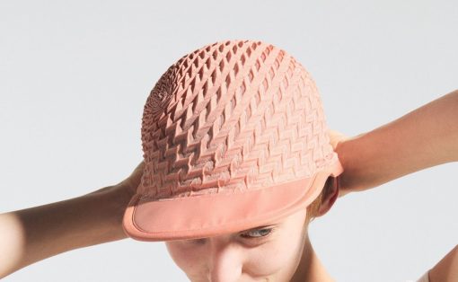 Person wearing a pink woven hat, tilting their head as it’s adjusted by their hands there.