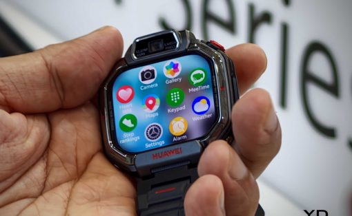Huawei smartwatch held in a hand, showing a colorful app grid on the screen (Camera, Gallery, Maps, Weather, Settings, Alarm) with a black metal band.