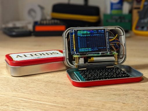 Portable DIY microcomputer built from an Altoids tin, featuring a small LCD display, exposed wiring, and a compact keyboard inside the lid