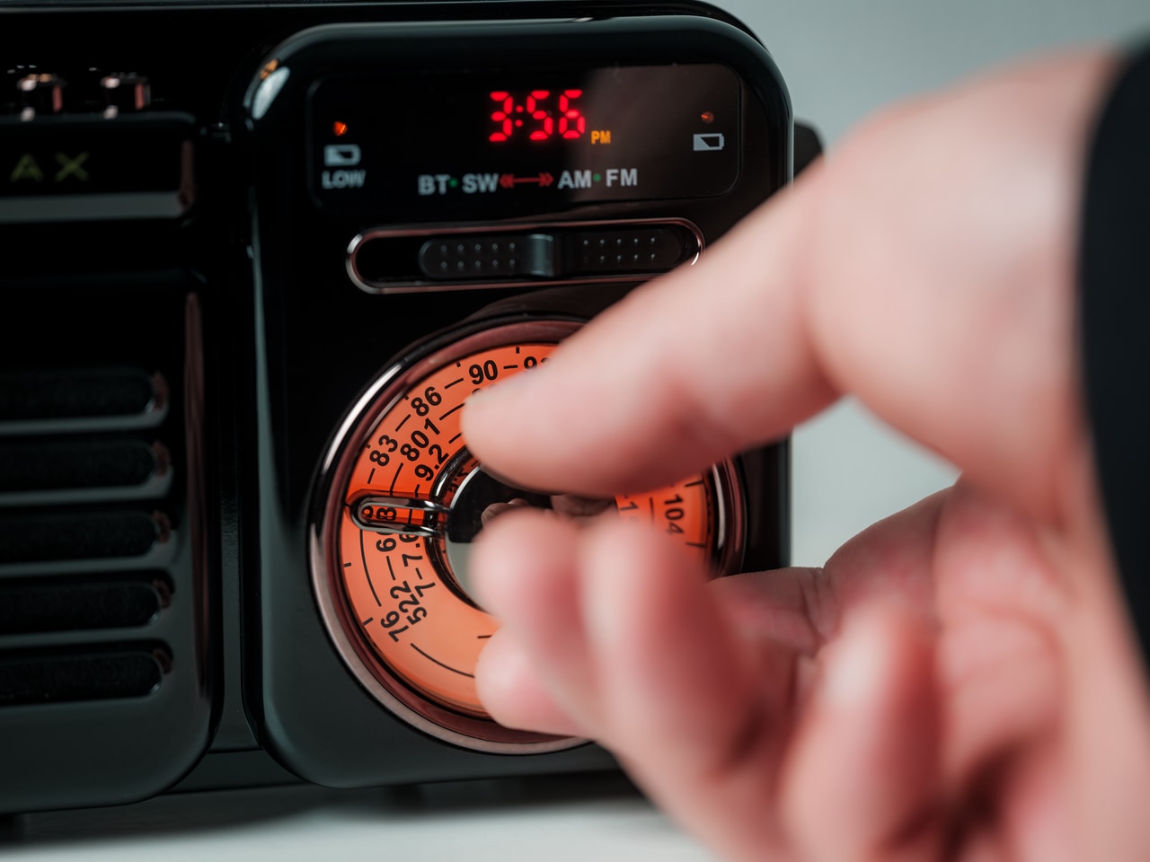 Close-up of a hand turning the orange dial on a car stereo/dashboard.