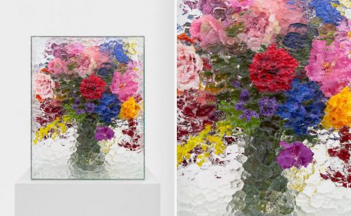 Vibrant, thickly textured floral painting in a glass frame on a white pedestal against a pale background.