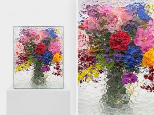 Vibrant, thickly textured floral painting in a glass frame on a white pedestal against a pale background.