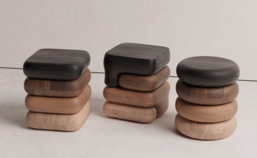 Three stacks of smooth, rounded wooden blocks in dark, mid, and light browns on a pale surface.