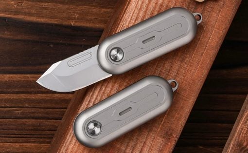 Two gray folding pocket knives on a wood surface, one blade extended.