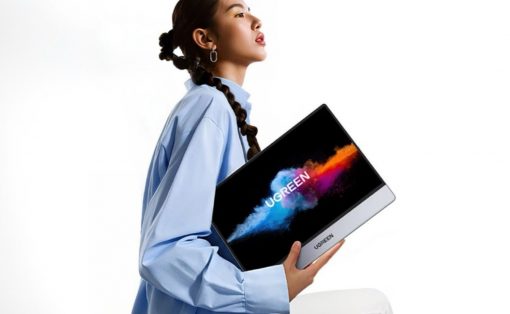 Young woman in a light blue shirt holds a UGREEN laptop/tablet with a colorful splash on the screen against a white background, highlighting the product shift image.