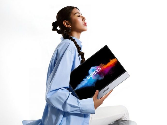 Young woman in a light blue shirt holds a UGREEN laptop/tablet with a colorful splash on the screen against a white background, highlighting the product shift image.