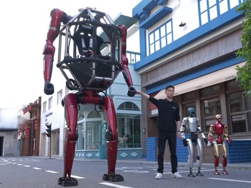 Man in a black shirt gestures toward a towering red humanoid robot on a city street, with silver and gold robots nearby.