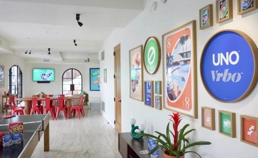 Bright game/lounge area with UNO-themed wall art, red metal chairs around a long table, and a ping-pong table on the left.