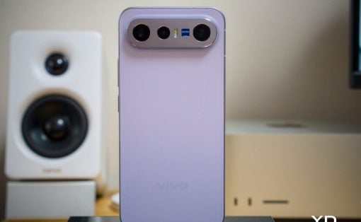 Purple Vivo smartphone standing upright on a desk, showing a triple camera module labeled Zeiss on the top edge.