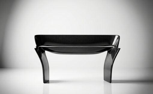 Carbon fiber bench with sculpted curved legs in a bright studio setting