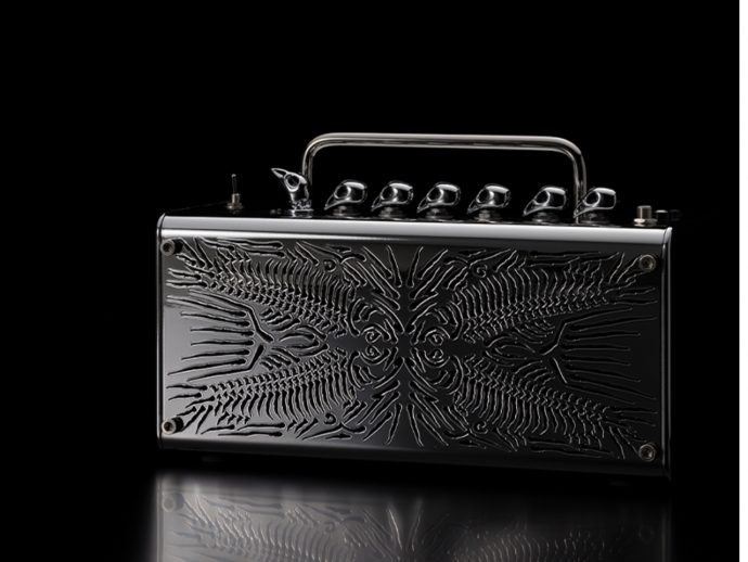 Shiny black metal case with a chrome handle and embossed abstract pattern, resting on a reflective surface against a black background.