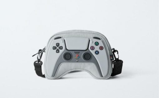 Grey PlayStation controller-shaped bag with buttons, hand straps, and adjustable crossbody strap.
