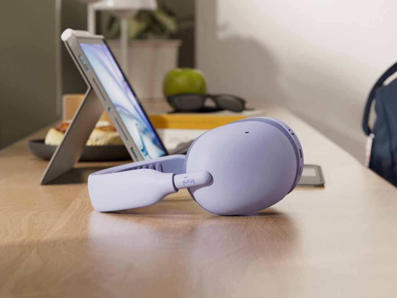 Lilac Logitech Zone Vibe Pro headphones resting on a desk beside a tablet