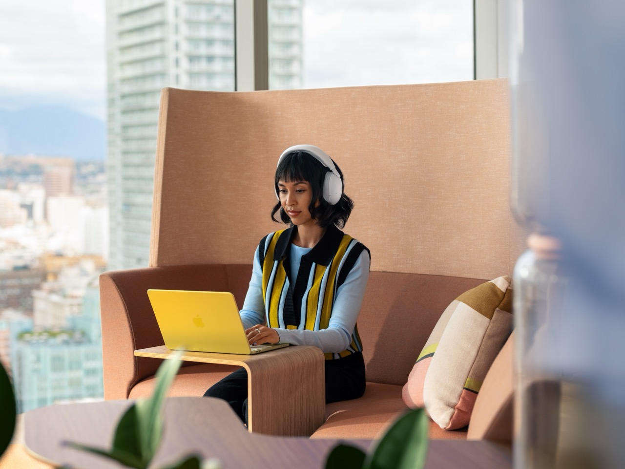Woman using a laptop while wearing off-white Logitech Zone Vibe Pro headphones