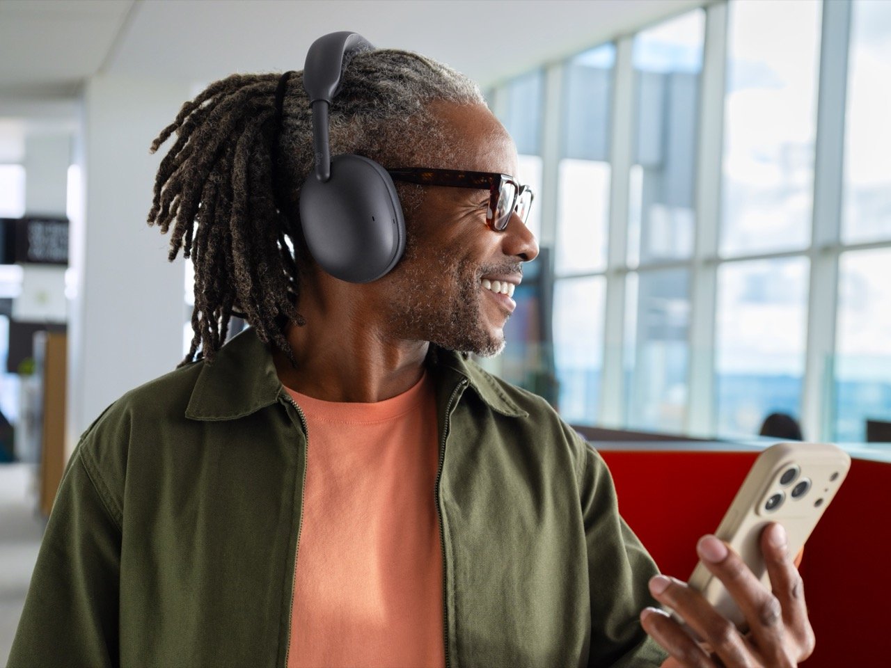 Man wearing graphite Logitech Zone Vibe Pro headphones while holding a smartphone